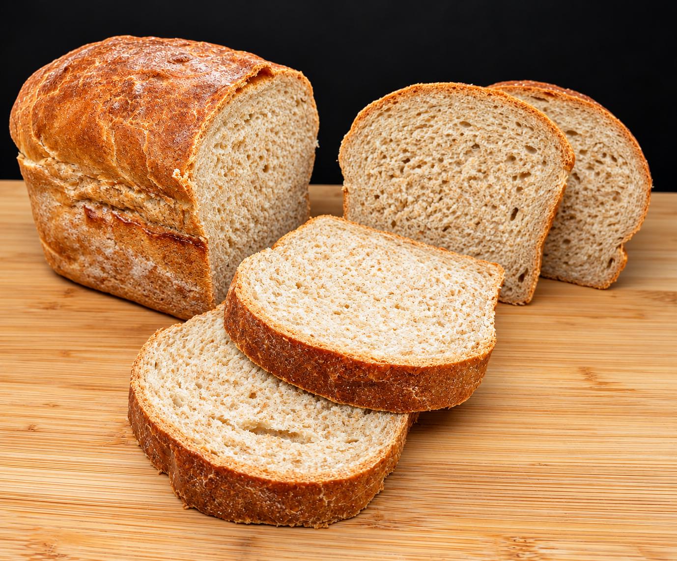 Pan de molde de masa madre con varias rebanadas cortadas sobre una tabla de madera